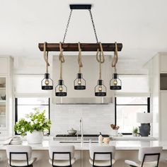 a kitchen with white cabinets and black chandelier hanging from the ceiling above it