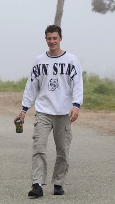 a man walking down the street with a beer in his hand