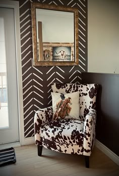 a cow print chair in front of a wall with a mirror on it's side