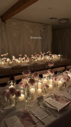 a long table is set with candles and flowers in vases, napkins and silverware