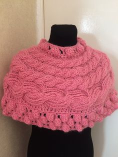 a pink knitted shawl sitting on top of a black mannequin head