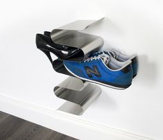 a pair of blue shoes hanging from the side of a white wall next to a black shoe holder