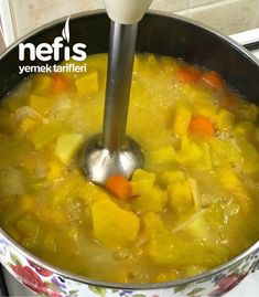 a pot filled with soup sitting on top of a stove next to a ladle