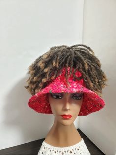 a mannequin head wearing a pink and red hat with dreadlocks on it