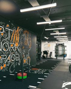 an indoor gym with black and white graffiti on the wall, exercise equipment in the foreground