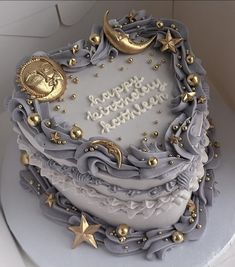 a birthday cake decorated with gold stars and moon decorations on a white tablecloth covered plate