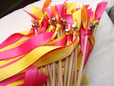 a bunch of pink and yellow sticks with some gold pins sticking out of them on a table