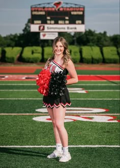 a cheerleader standing on the field with her pom poms