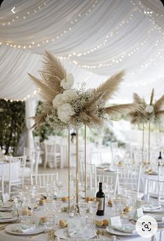 the tables are set with white linens, gold chargers and tall centerpieces