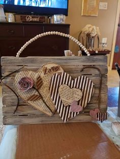 a wooden box with two hearts on it sitting on a table in front of a television