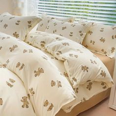 a bed with white sheets and teddy bears on it, in front of a window