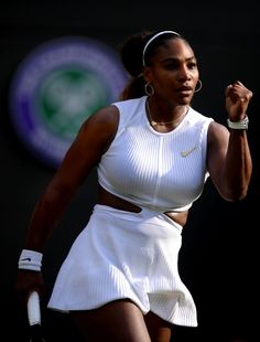 a woman holding a tennis racquet on top of a tennis court with her hand in the air