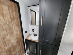 a bathroom with black cabinets and a white sink in the corner next to a wooden door