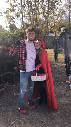 a man and woman dressed up in costumes posing for a photo with halloween decorations behind them