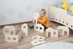 a young child playing with wooden toys on the floor in a room that looks like a bedroom