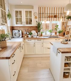 a kitchen filled with lots of white cabinets and wooden counter tops next to a window