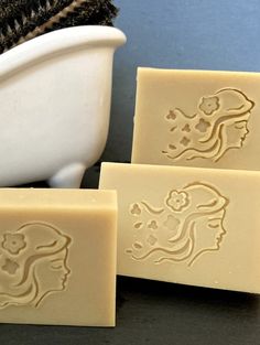 three soap bars sitting on top of a counter next to a white bowl and towel