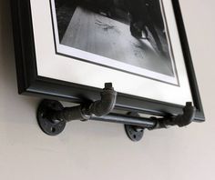 a black and white photo hanging on the wall next to a coat rack with an iron pipe