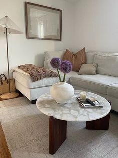 a living room with white couches and a marble coffee table in the center area