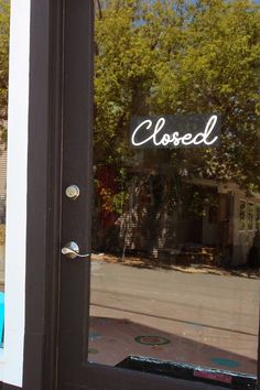 a closed store front door with the reflection of trees in it