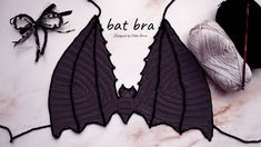 a crochet bat bra next to a ball of yarn