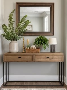 a wooden table topped with a mirror next to a potted plant and a lamp