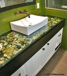 a white sink sitting on top of a counter next to a green tiled bathroom wall