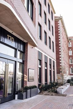 the entrance to an apartment building with large windows and brick walkway leading up to it