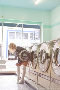 a woman standing in front of a row of washers next to each other on the floor