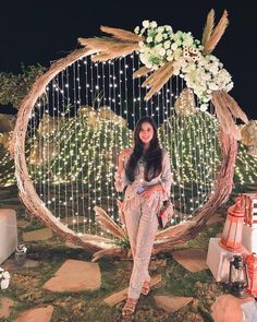 a woman is sitting in front of a circular display with lights and flowers on it