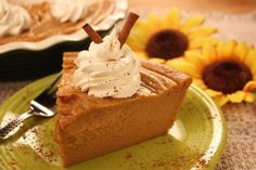 a slice of pumpkin pie with whipped cream on top and sunflowers in the background