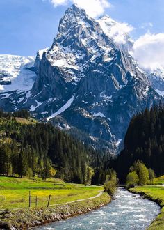 there is a mountain with snow on it and a river running through the valley below