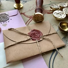 a wax stamp on top of a brown envelope with twine and some other crafting supplies next to it