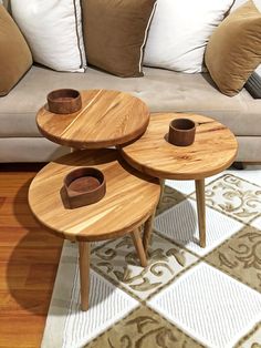 three wooden tables sitting on top of a white rug in front of a beige couch