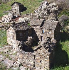 an old stone building sitting on top of a lush green hillside