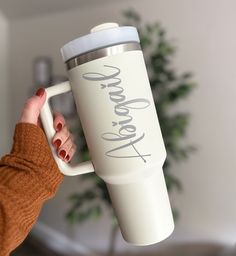 a woman holding a white coffee cup with the words welcome on it