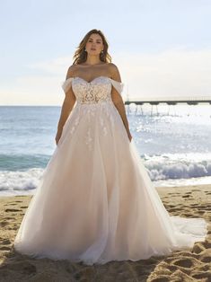 a woman in a wedding dress standing on the beach