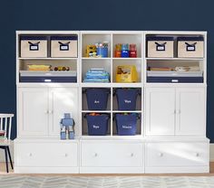 a white bookcase with blue bins and two chairs in front of the bookshelf