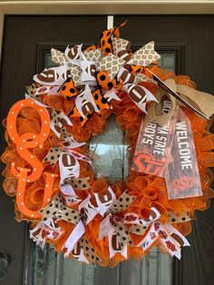 an orange and white wreath with the word boo on it is sitting in front of a door