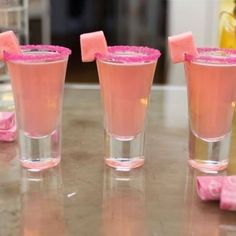 three glasses filled with pink liquid sitting on top of a table next to each other