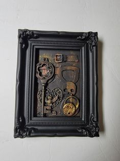 there is a black frame with keys and other things in it that are attached to the wall