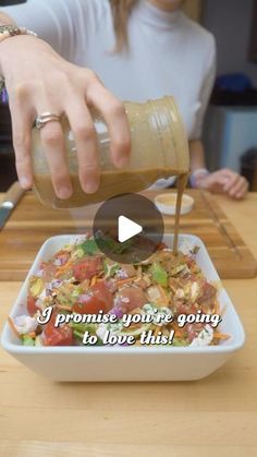 a woman is pouring dressing into a bowl