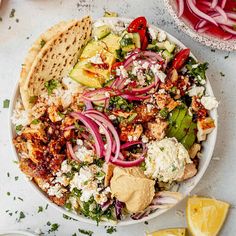 a bowl filled with salad and pita bread on top of a white table next to sliced