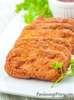 three fried chicken patties on a white plate with parsley and ketchup