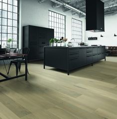 a large kitchen with wooden floors and black cabinets in an industrial style home or office