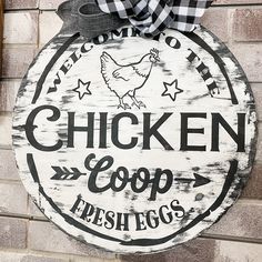 a chicken coop sign hanging on the side of a brick building with a bow around it's neck