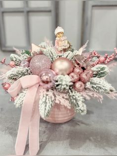 a pink vase filled with ornaments on top of a table