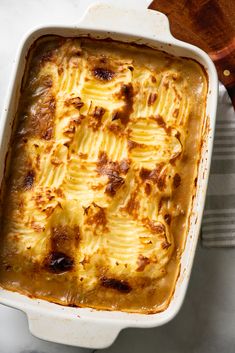 a casserole dish with cheese and meat in it on a white tablecloth