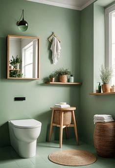 a bathroom with green walls and flooring next to a white toilet in front of a window