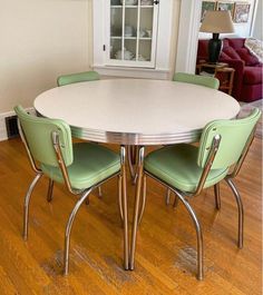 a white table with green chairs in a room